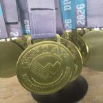 Close-up of gold medals with blue ribbons hanging from display hooks, ready for award ceremony.